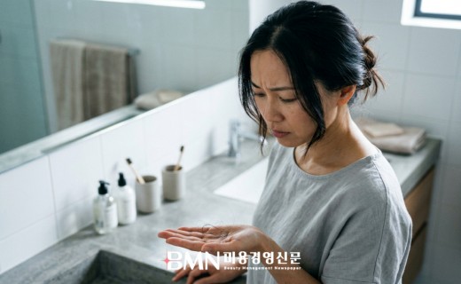 빠진 머리카락을 손에 들고 걱정스럽게 바라보는 여성