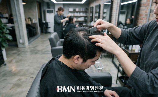 살롱에서 정수리 두피를 확인받는 20대 남성 고객