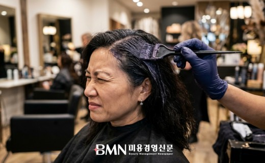 새치 염색 시술 중 두피 자극에 미간을 찌푸리는 고객
